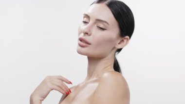 Omuzlarına dokunan kadın pürüzsüz parlak tenini gösteriyor