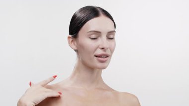 Kadın usulca gülümserken çıplak omzuna dokunuyor.