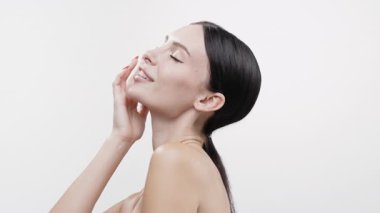 Gülümseyen kadın yumuşak, parlak tenine dokunuyor.