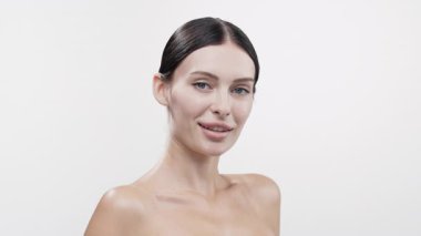 Beyaz arka planda poz veren gülümseyen genç kadın