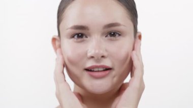 Genç kadın yumuşak, parlak yanaklara dokunuyor nazikçe gülümsüyor.