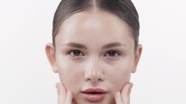 Genç bir kadın pürüzsüz, parlak cildine dokunuyor.