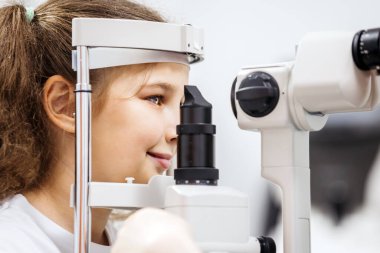 Genç kız, göz tedavisiyle özel göz teçhizatı kullanarak, pediatrik göz bakımının önemini vurgulayarak ve sağlık bilincini artırarak meşgul edilmektedir.