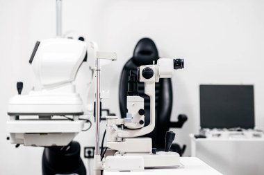 Modern oftalmoloji muayene odasında, yarık lamba ve göz muayenesi koltuğu da dahil olmak üzere ileri seviye teşhis ekipmanları sergilenirken, göz sağlığı ve hasta bakımının önemini vurguluyor.