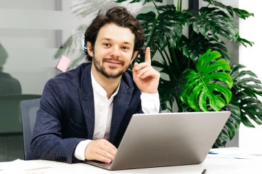 Masada oturan adam parmağıyla işaret ediyor.