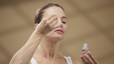 Kadın cam damlası kullanarak yüz serumu uyguluyor.