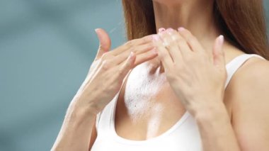 Kadın boynuna nemlendirici sürüyor.