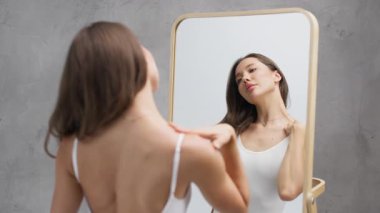 Genç bir kadın büyük aynada kendine hayran.