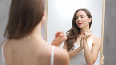Banyo aynasında kendine hayran olan genç bir kadın.