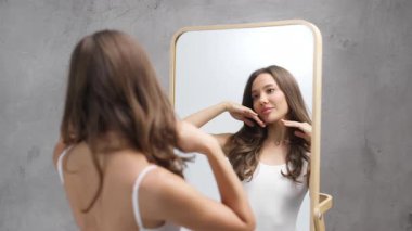 Genç bir kadın aynadaki yansımasına hayran.
