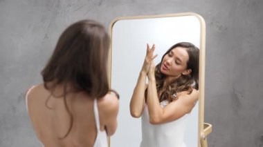 Ayna yüzeyine dokunurken yansımaya hayran olan kadın