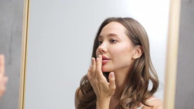Genç bir kadın nazikçe dudak kremi sürüyor.