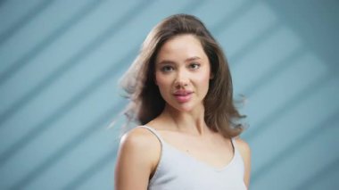 Mavi çizgili arka planda poz veren genç bir kadın