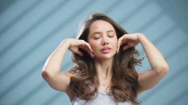 Genç bir kadın evde dinlenirken yüzüne dokunuyor.