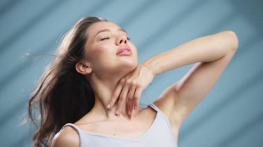 Güneş ışığından hoşlanan genç bir kadın zarif bir şekilde boynuna dokunuyor.