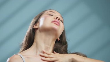 Kafasını arkaya eğen kadın pürüzsüz boyun derisine dokunuyor