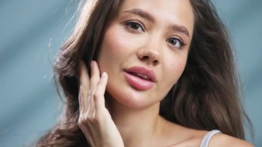 Genç bir kadın yüzüne nazik bir ifadeyle dokunuyor.