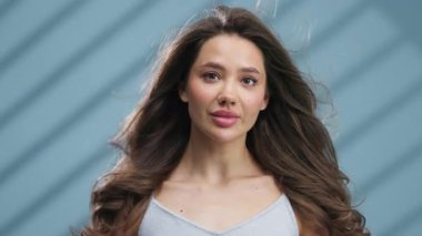 Açık havada gülümseyen genç bir kadın dalgalı saçlarıyla