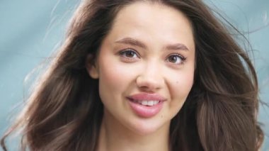 Açık havada dalgalı kahverengi saçlı, gülümseyen genç bir kadın.