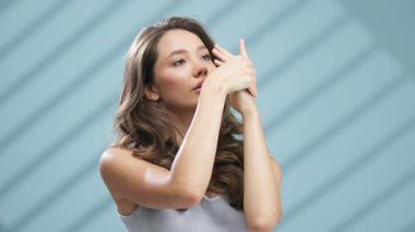 Mavi arka planda zarif poz veren genç bayan.