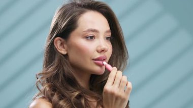 Düşünceli bir ifadeyle pembe ruj süren bir kadın.