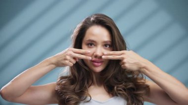 Yanaklarını esneterek gülümseyen genç bir kadın.