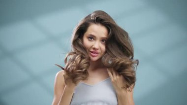 Gülümseyen kadın uzun dalgalı kahverengi saçlara dokunuyor