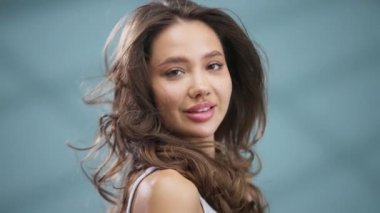 Kahverengi saçlı, gülümseyen genç bir kadın.