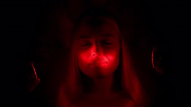 Karanlıkta parlayan kırmızı ışıkla aydınlanan kadın