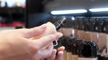 Sıvı temel şişesini kozmetik bölümünde tutan kişi