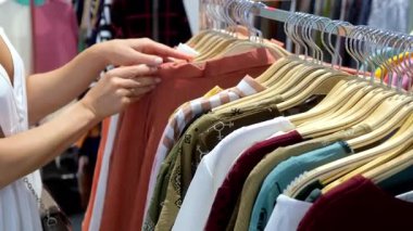 Askıda asılı renkli gömleklere göz atan kişi