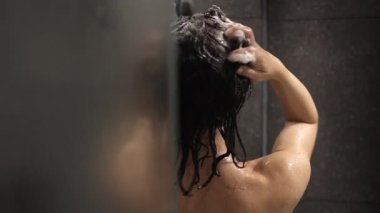 Rahatlatıcı duş sırasında saç yıkayan kişi