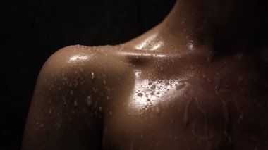 Dramatik ışıklandırma altında parıldayan ıslak omuz