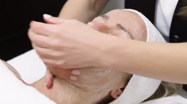 Kaplıcada rahatlatıcı yüz bakımı gören bir kadın