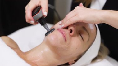 Kadın güzellik kliniğinde yüz bakımı görüyor.