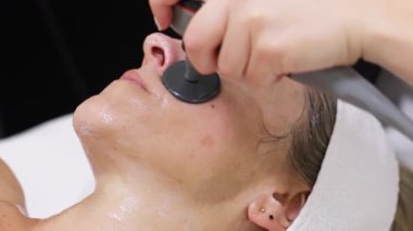 Kadın elektronik cihaz kullanarak yüz tedavisi görüyor