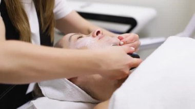 Kaplıcada rahatlatıcı yüz bakımı gören bir adam