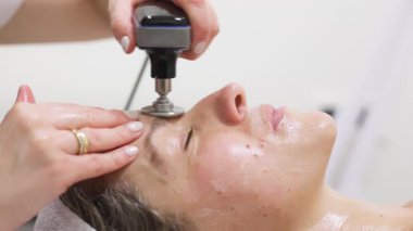 Cihaz kullanılarak yüz bakımı gören kadın