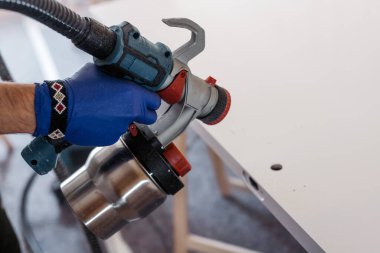 Kapalı alanda boya spreyi kullanan eldiven giyen biri.