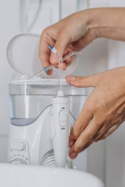 Eller diş temizliği için modern su temizleyicisini hazırlıyor.