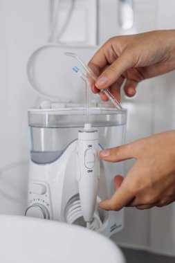 Beyaz su diş ipi aygıtının içine nozül yerleştiren kişi