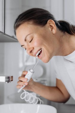 Gülümseyen kadın beyaz su diş ipi kullanıyor.