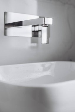 Beyaz seramik lavabonun üzerinde modern krom musluk