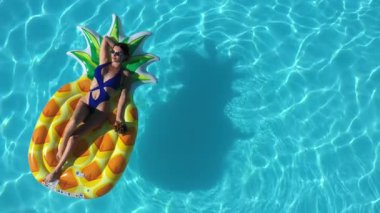 Ananaslı bir kadın havuzda yüzüyor.