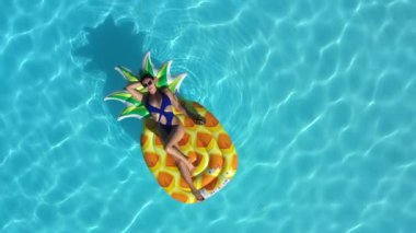 Ananaslı bir kadın havuzda yüzüyor.