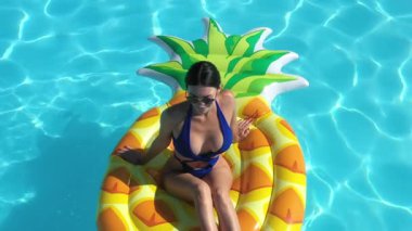 Ananaslı bir kadın havuzda yüzüyor.