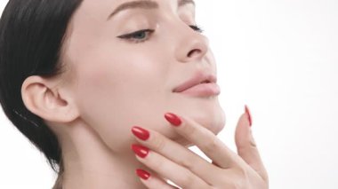 Kırmızı tırnaklı bir kadın yüzüne dokunuyor
