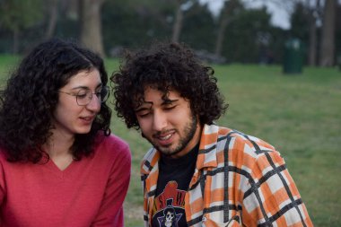 Friends couple sitted at the park talking and having fun 