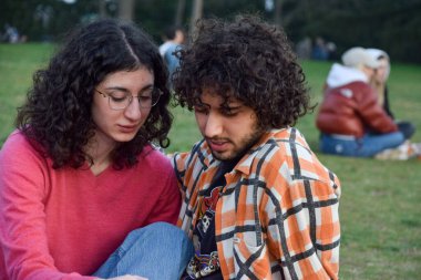 Romantik çift parkta oturmuş birlikte kitap okuyorlardı..