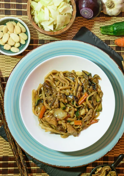 stock image Rice noodles with vegetables and meat in white bowl. Wood background. Close up. Top view